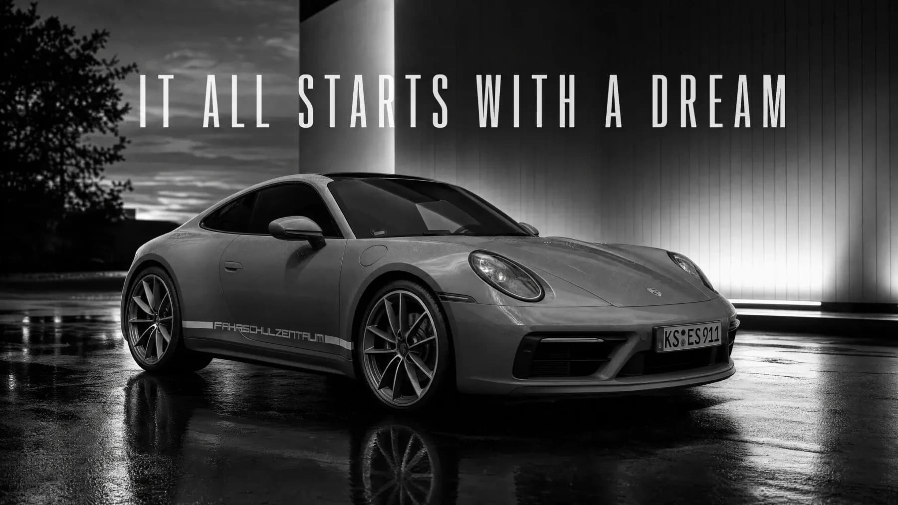 Keyvisual eines Porsche 911 im Design des Fahrschulzentrums mit dem Schriftzug It all starts with a dream