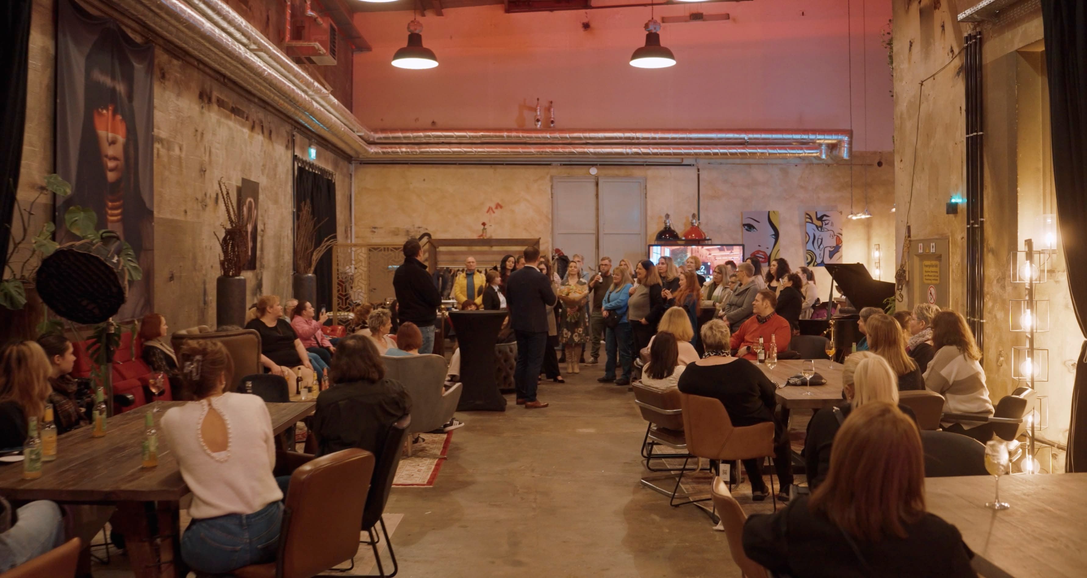 Das Team von Home Instead beim Teamevent in der Industrie-Eventlocation Konzept 9 in Kassel, im Vordergrund der Übergabe-Moment mit Blumenstrauß