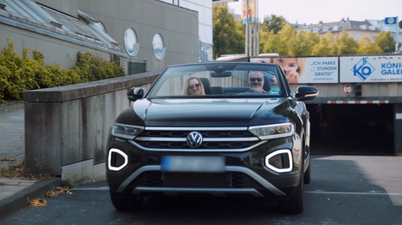 Ein Paar im schwarzen Cabrio fährt entspannt aus der Tiefgarage Friedrichsplatz heraus